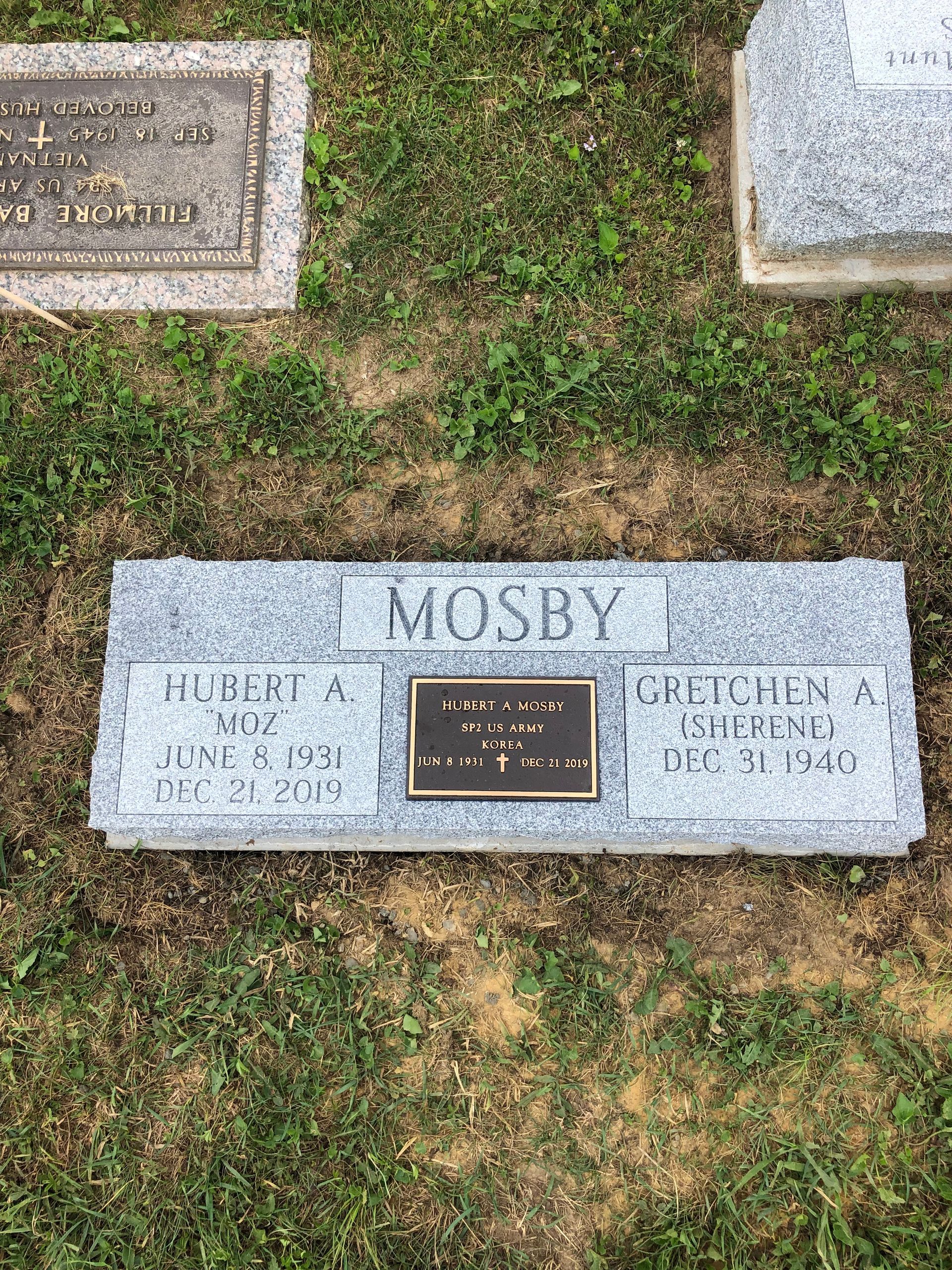 Gravestone for Mosby in a grassy cemetery, with two adjacent markers partially visible.