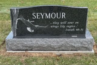 Black granite memorial headstone engraved “SEYMOUR” with a dove and Bible verse in a grassy cemetery.