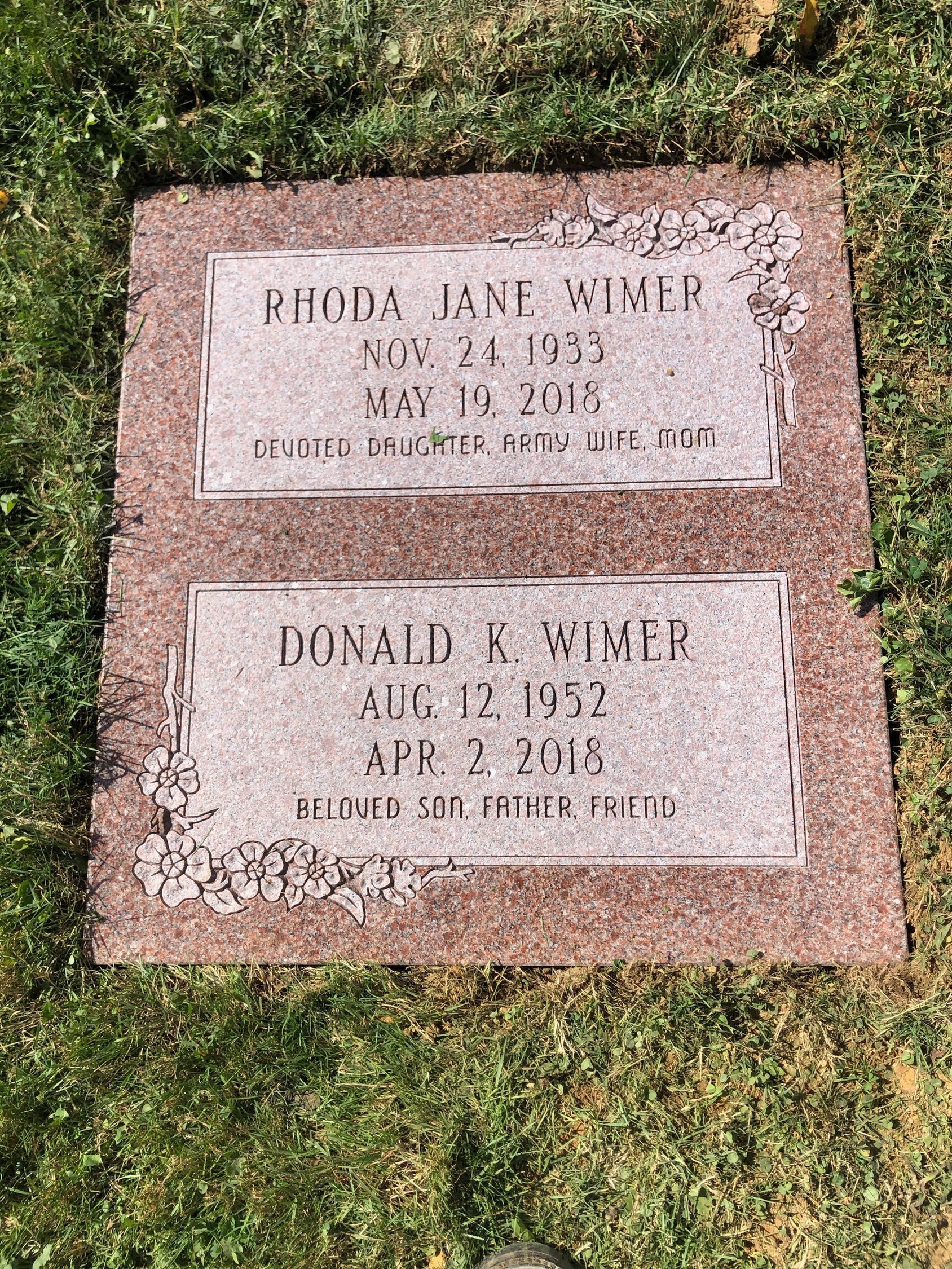 Two engraved memorial plaques in pink stone set in grass