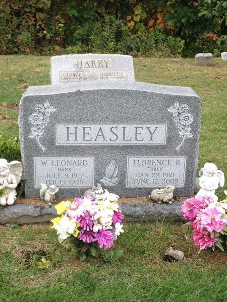 Heasley family gravestone in a cemetery, with pink and white flowers at the base.