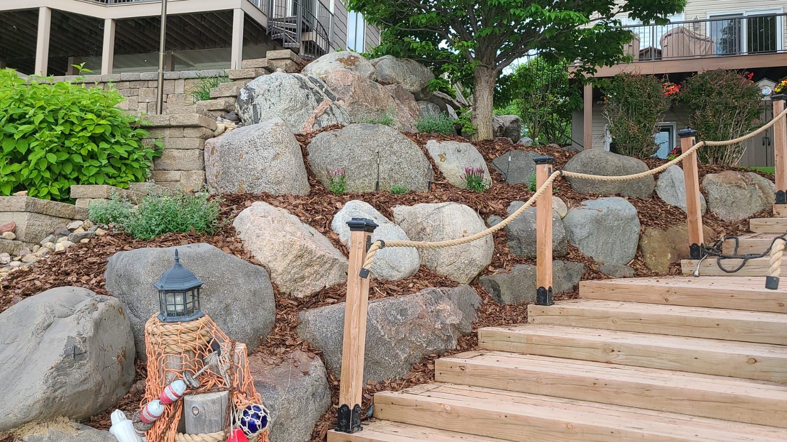 A wooden deck with stairs leading up to a rock wall.