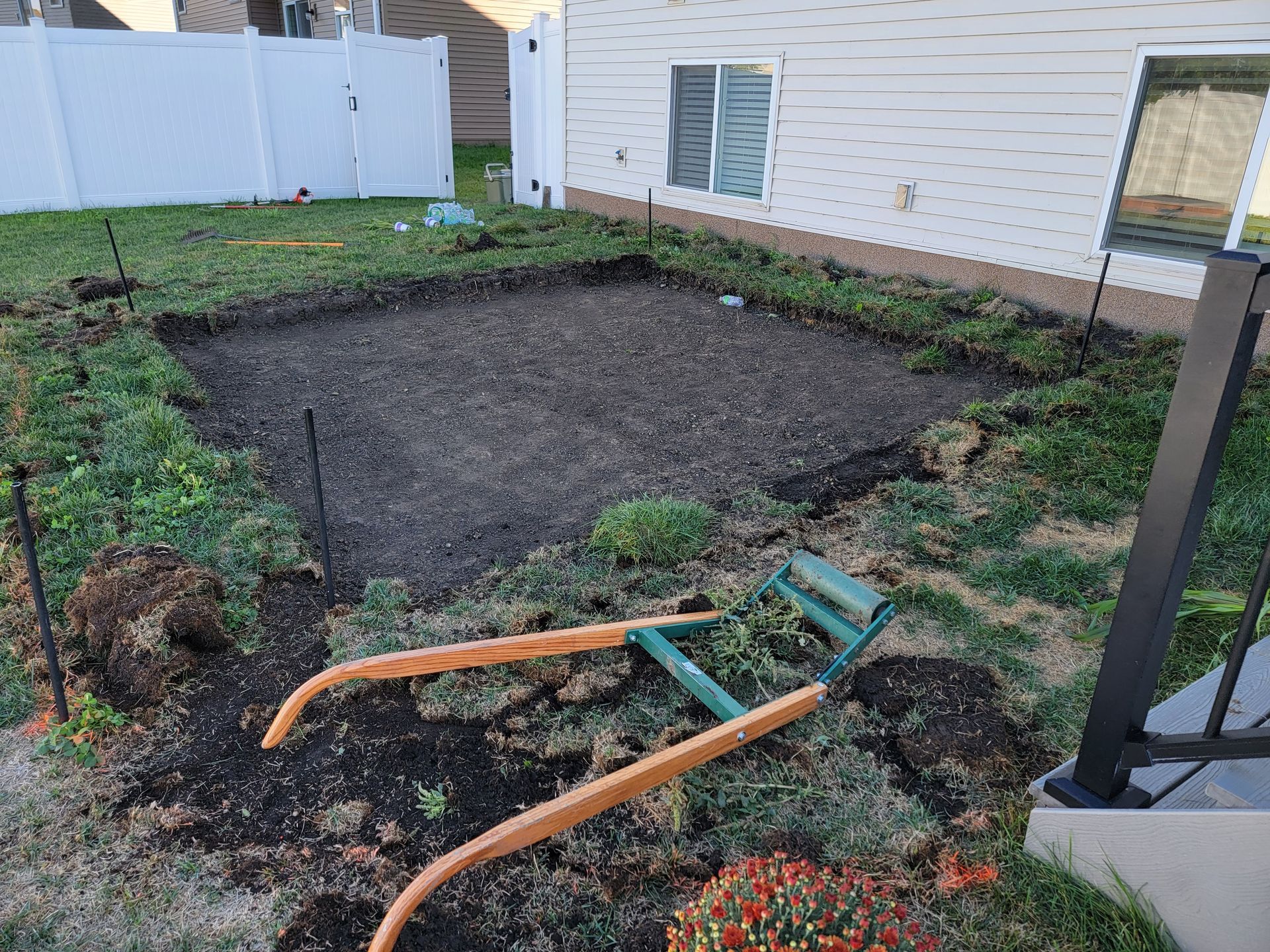 A wheelbarrow is sitting in the dirt in front of a house.