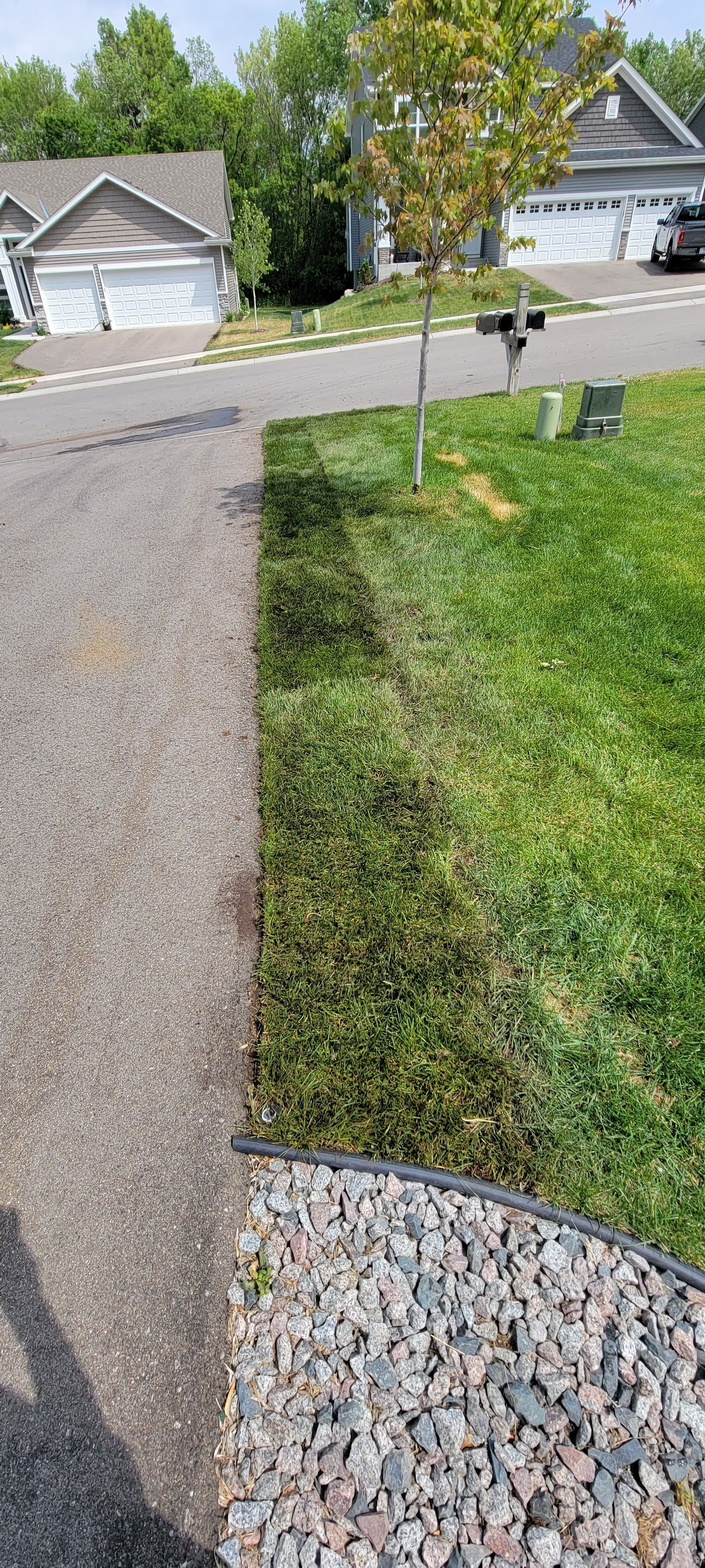 A gravel driveway leading to a house in a residential neighborhood.