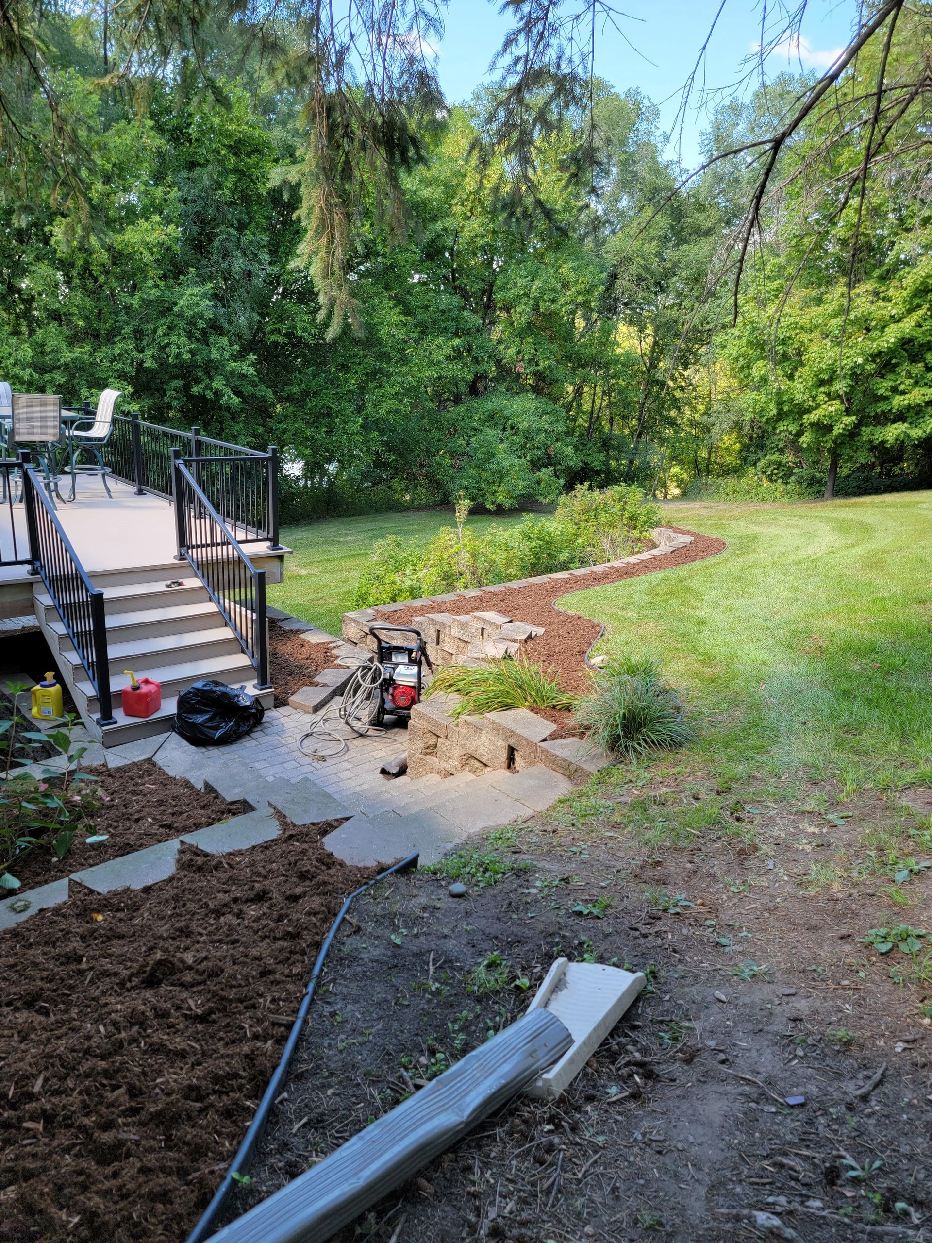 A backyard with stairs leading up to a deck and trees in the background.