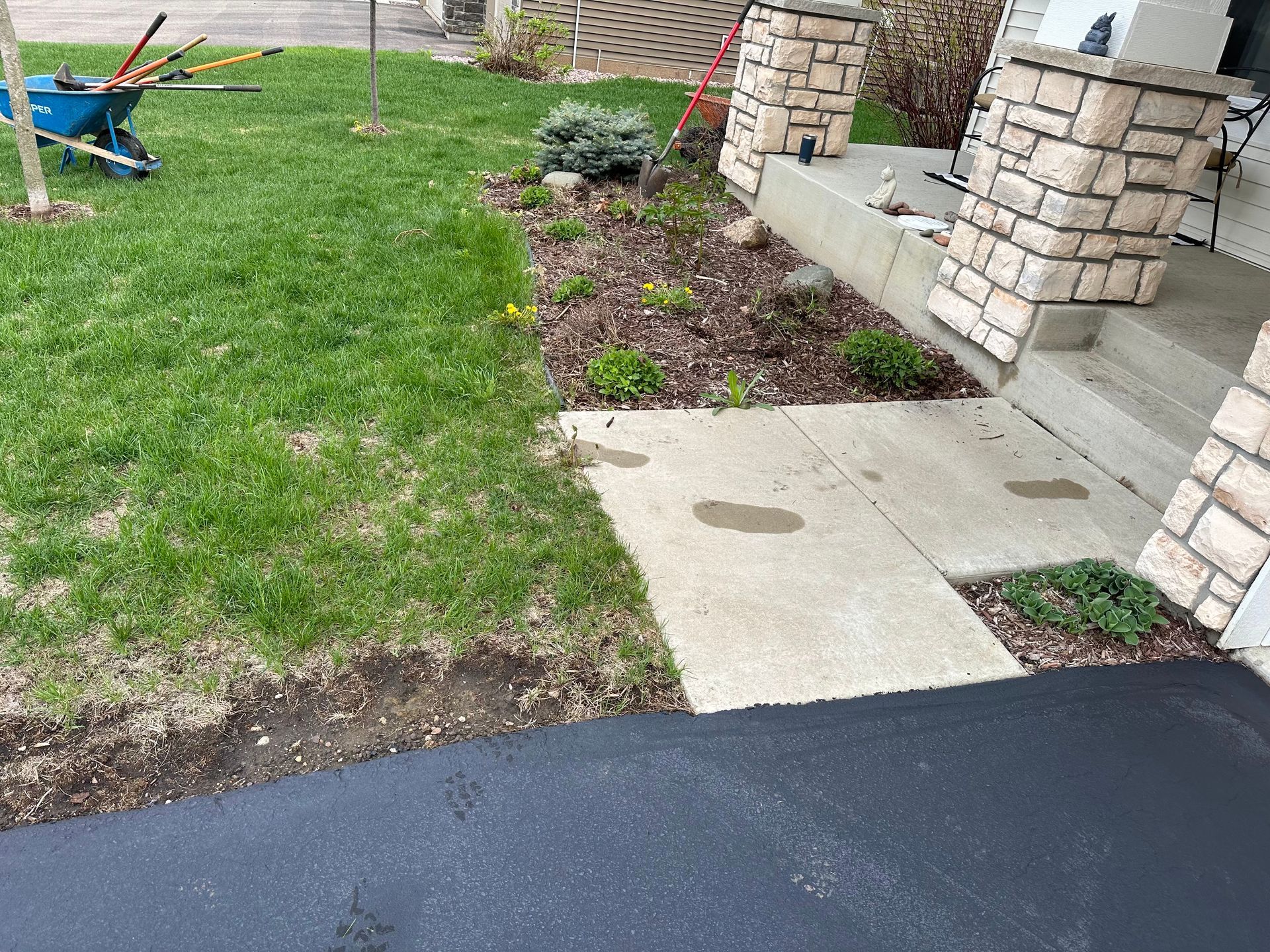 A wheelbarrow is parked in the grass in front of a house.