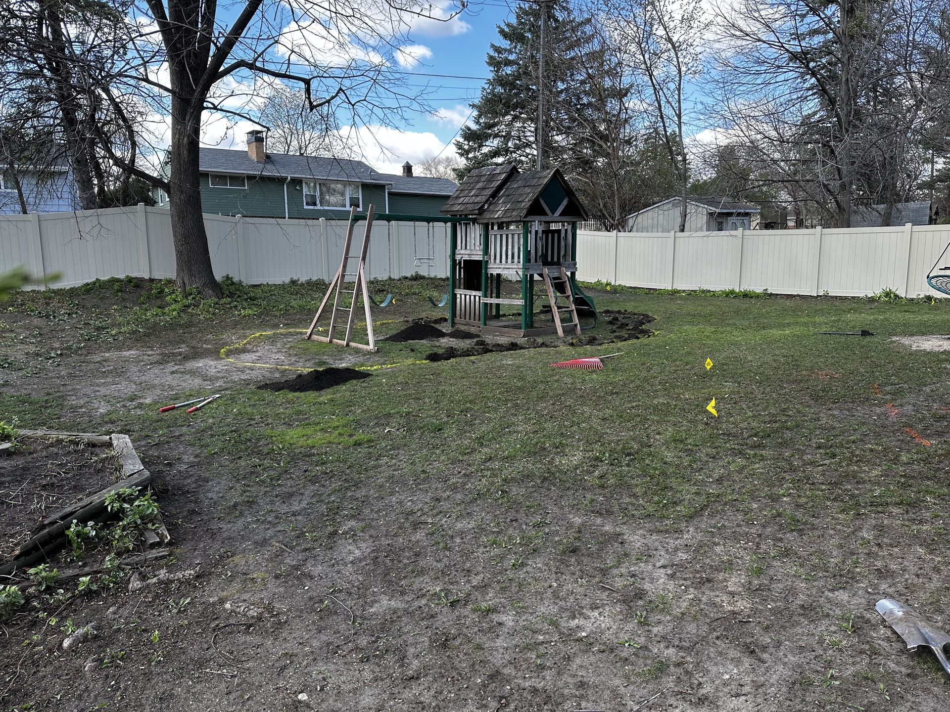 A backyard with a swing set and a house in the background.