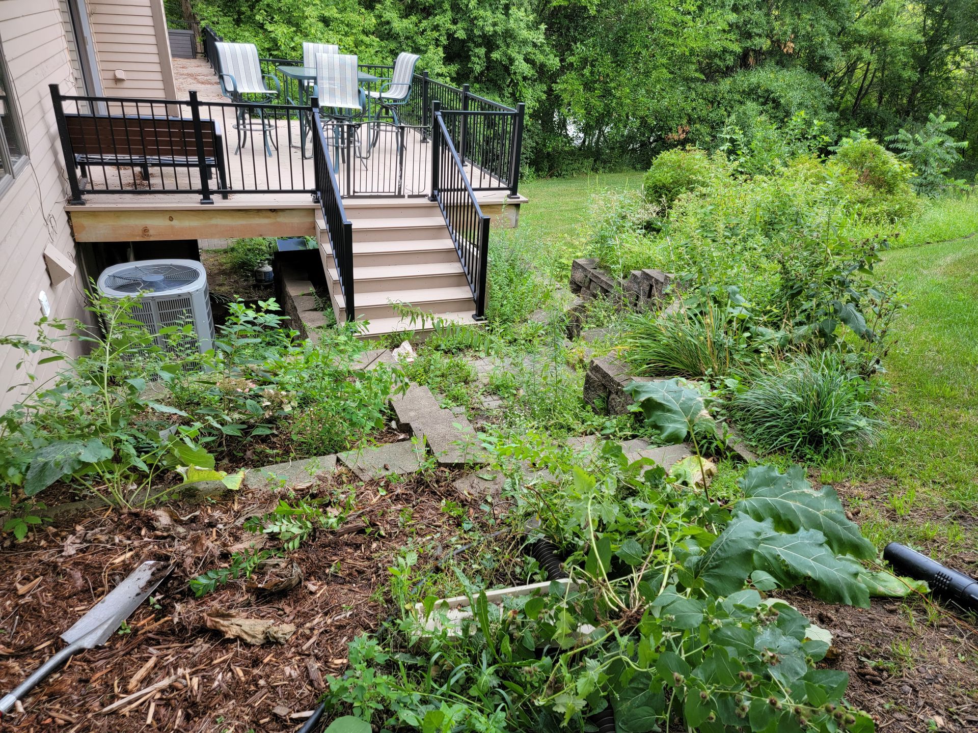 A garden with a deck and stairs in the background.