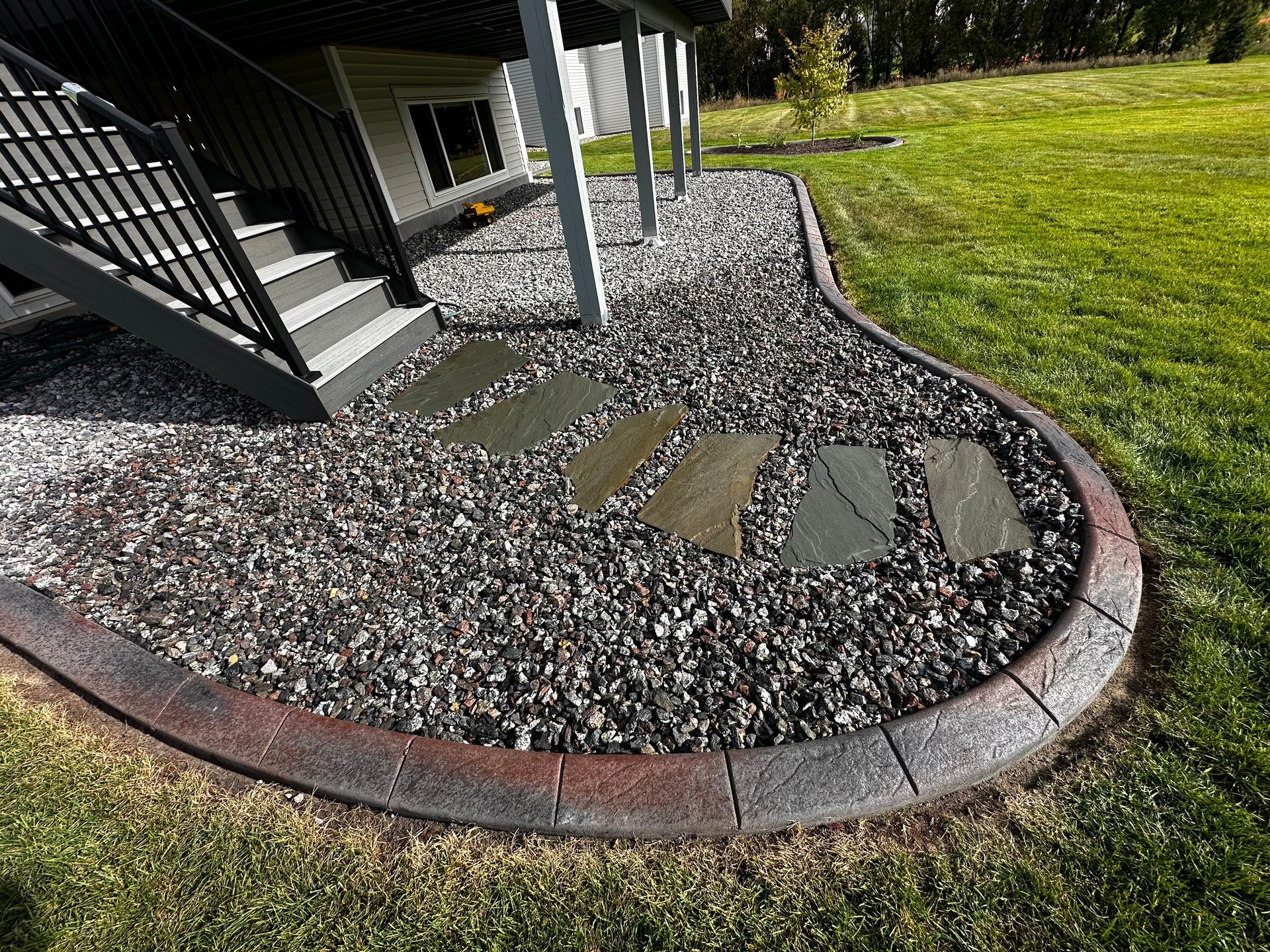 A walkway with gravel and rocks in front of a house.