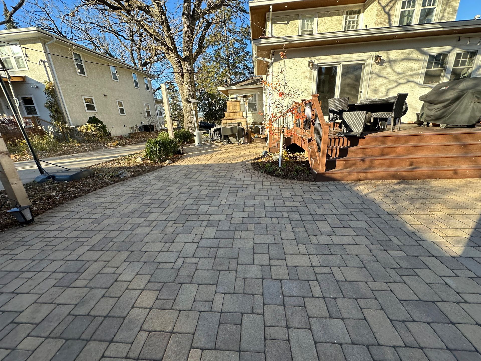 A brick patio with a wooden deck in front of a house.