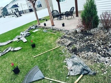 A bunch of gardening tools are laying on the grass in a yard.