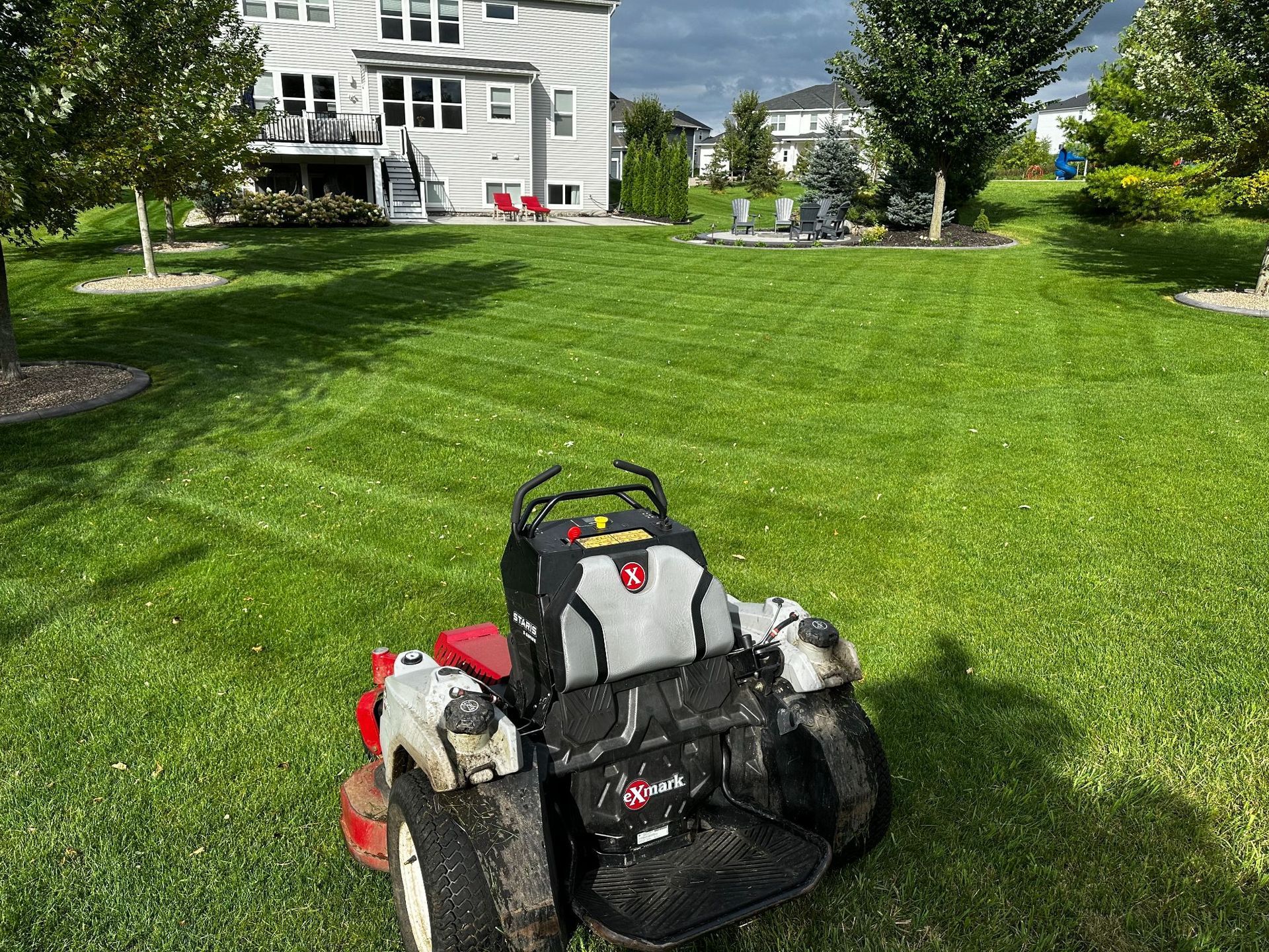 A man is mowing a lush green lawn with a lawn mower.