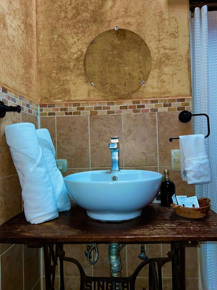 Lavabo de baño con encimera de madera, lavabo azul claro, espejo de pared, dispensador de jabón y toallero.