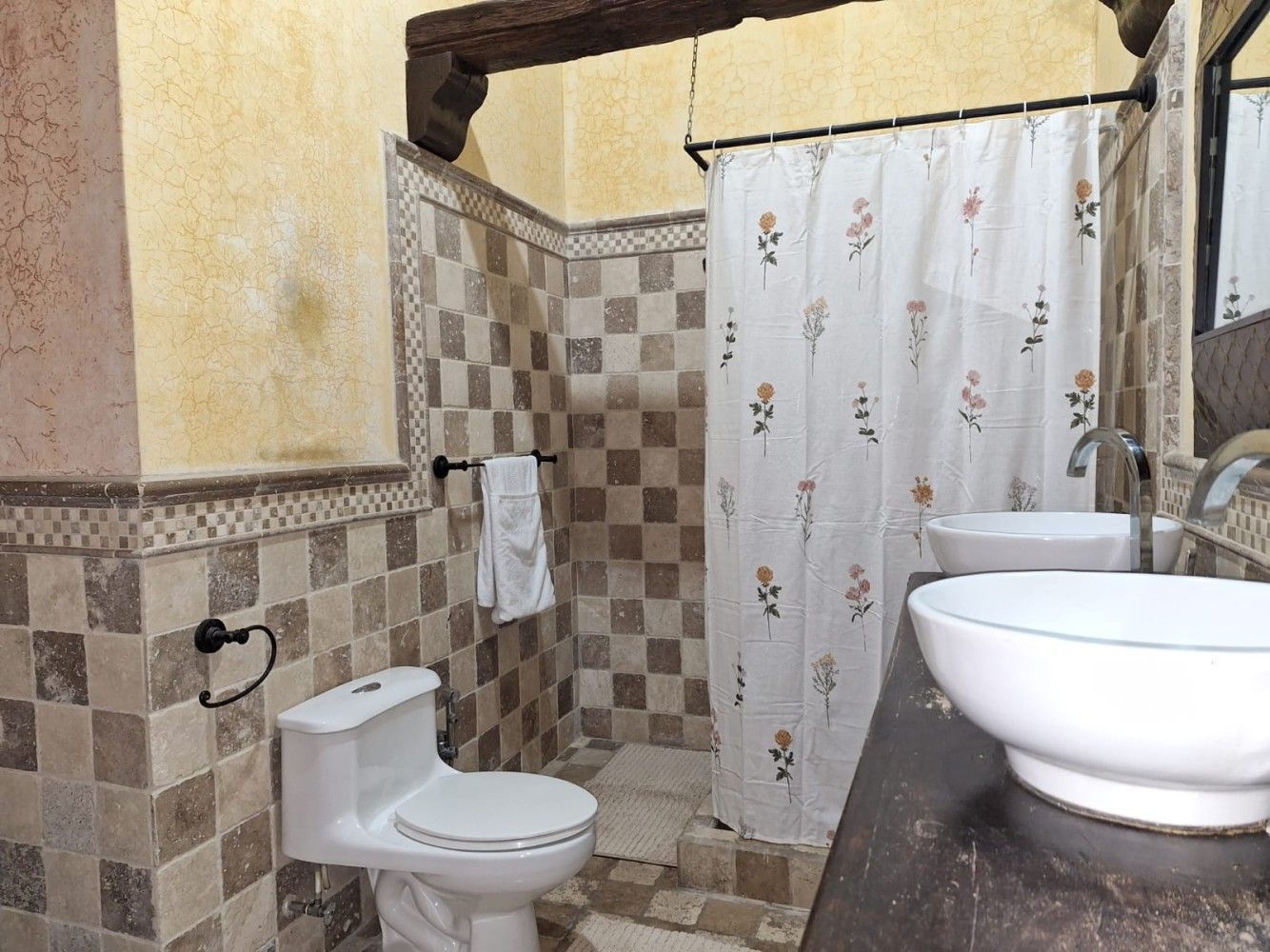 Baño pequeño con inodoro, cortina de ducha, paredes alicatadas y encimera con lavabo.