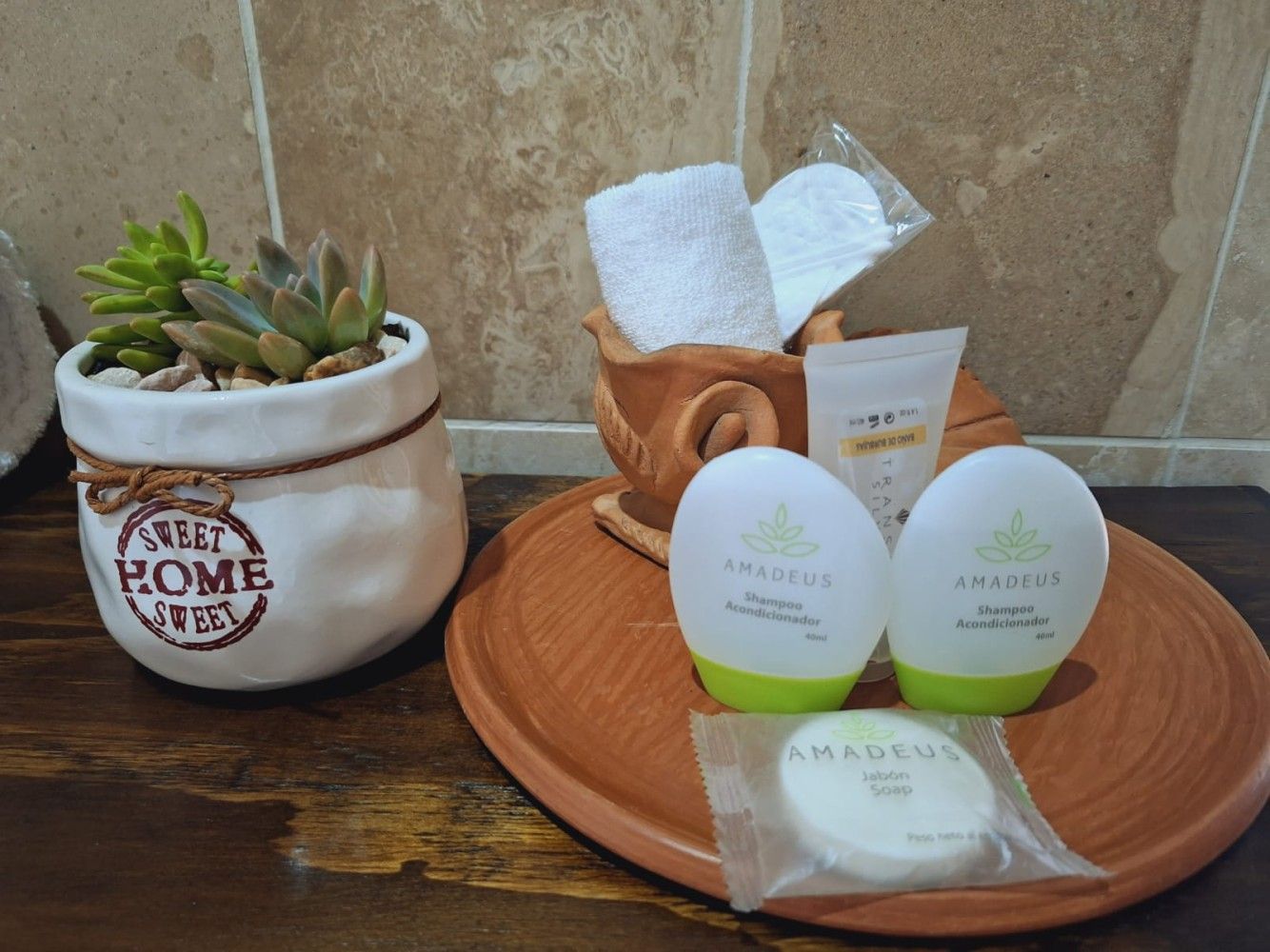 Estantería de baño con tarros blancos, jabones y una bandeja de terracota sobre una encimera de azulejos.