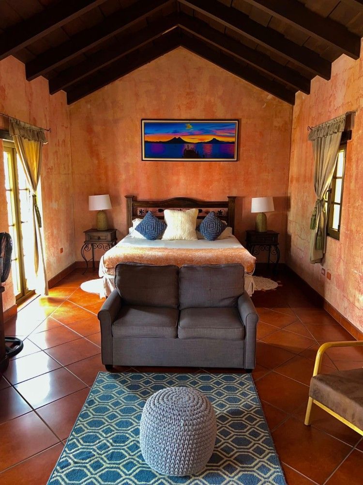 Acogedora habitación con cama, sillón, alfombra estampada y techo y paredes revestidos de cálidos paneles de madera.