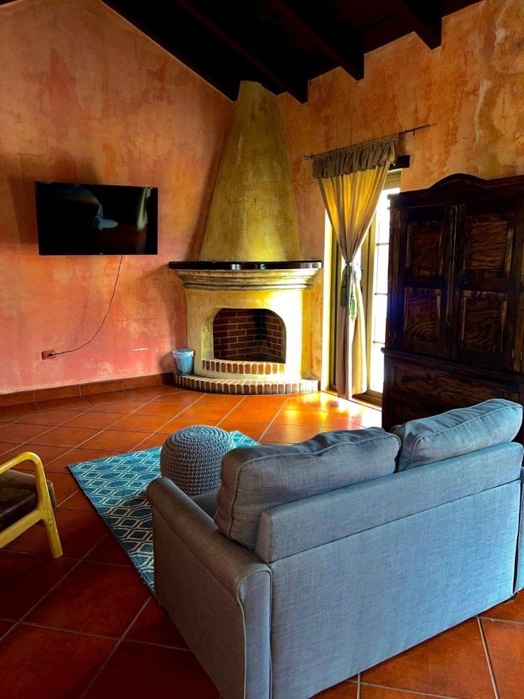 Acogedora sala de estar con sofá gris, chimenea, televisor empotrado en la pared y paredes de color naranja cálido.
