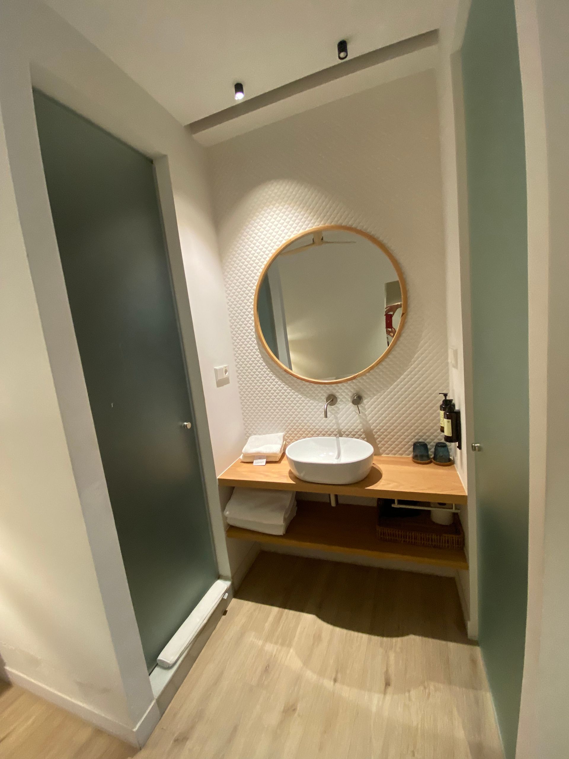 A bathroom with a sink and a round mirror