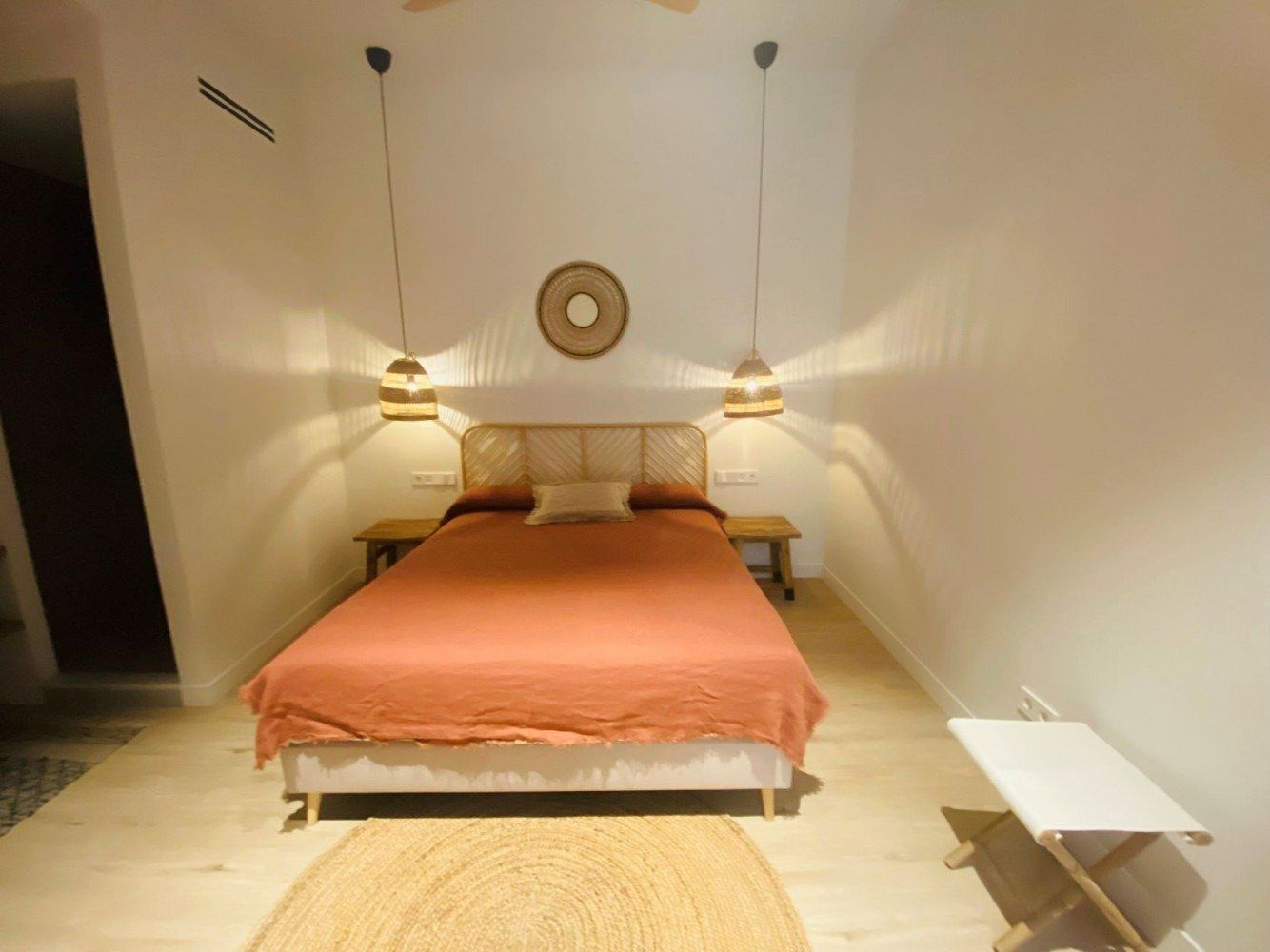 A bedroom with a large bed and a rug on the floor.