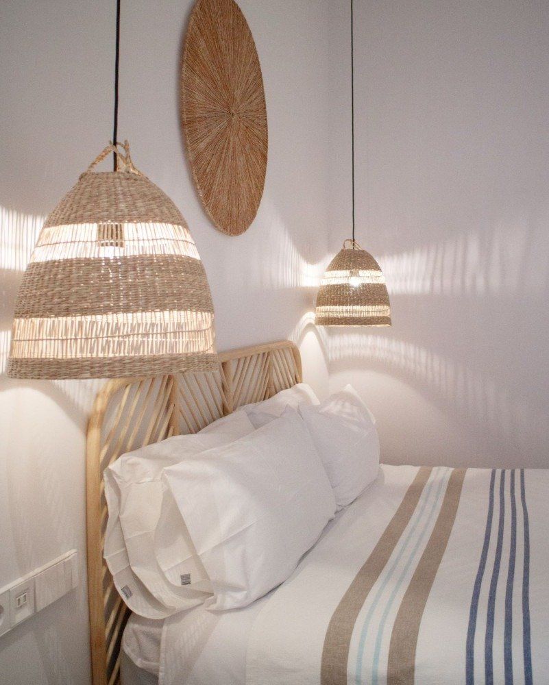 A bedroom with a bed and wicker lamps hanging from the ceiling