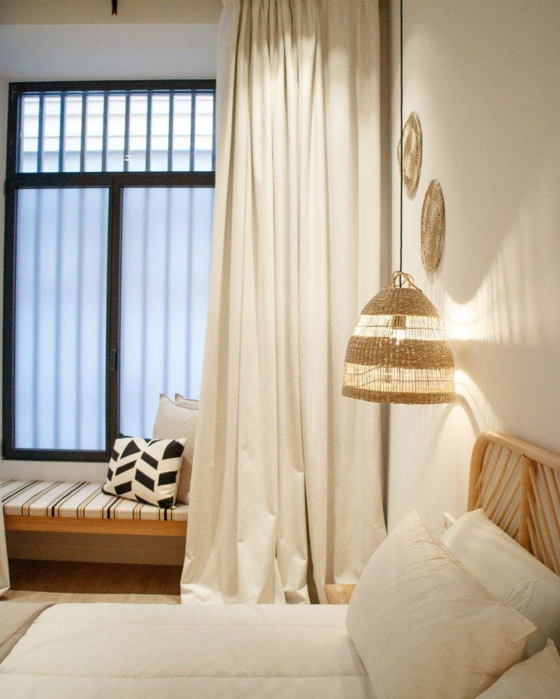 A bedroom with a bed and a window with white curtains