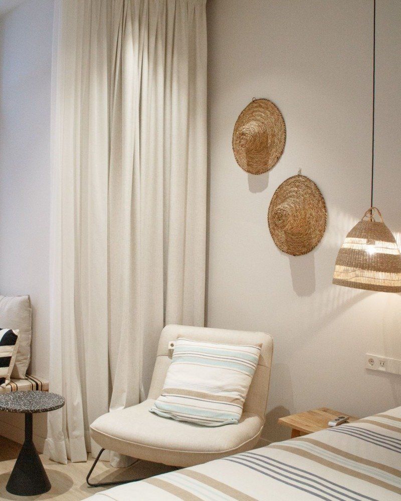 A bedroom with a bed , chair , table and two hats on the wall.