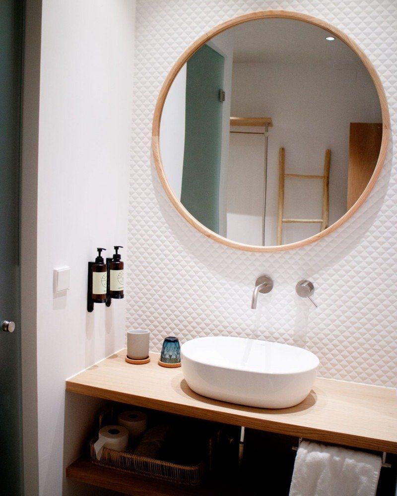 A bathroom with a sink and a round mirror