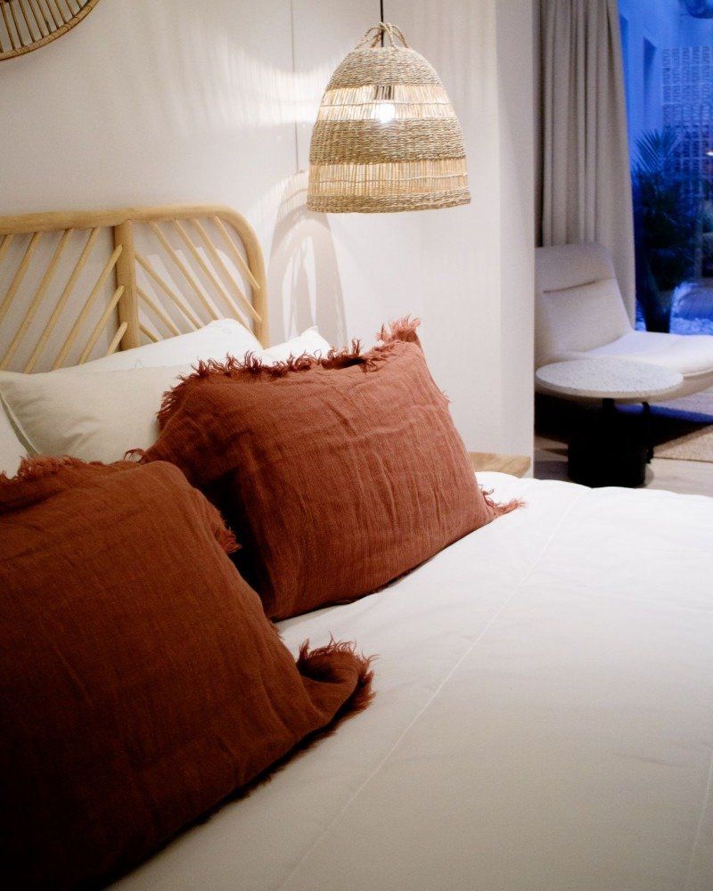 A bed with two pillows and a lamp hanging from the ceiling
