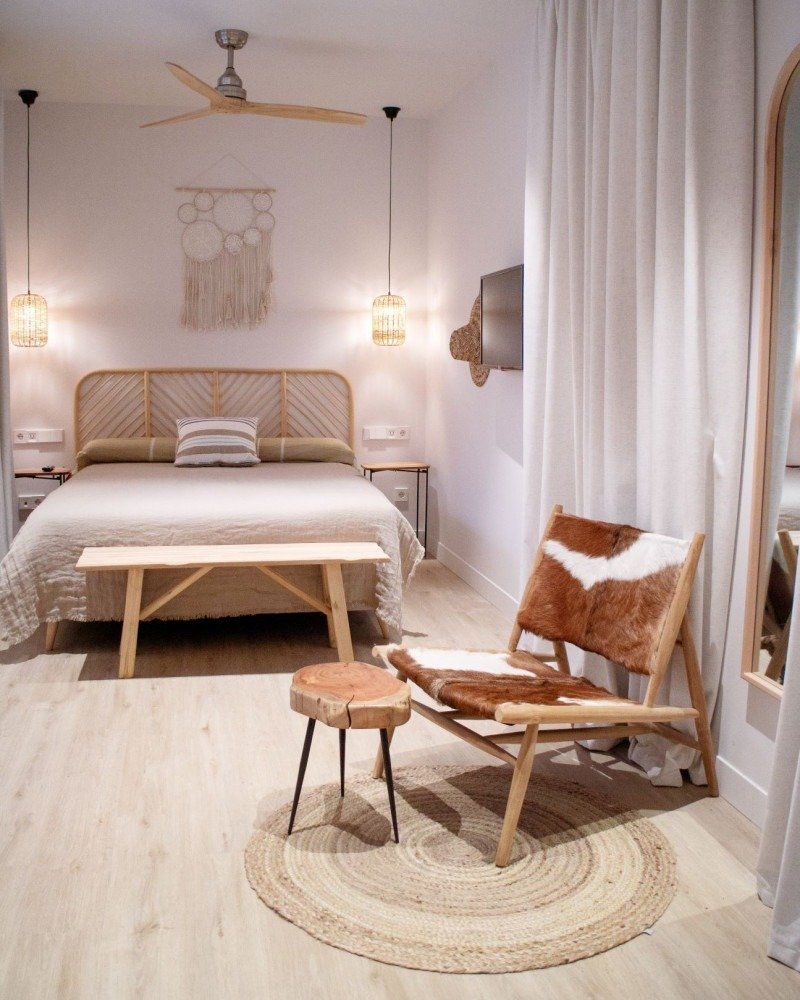 A bedroom with a bed , chair , table and mirror