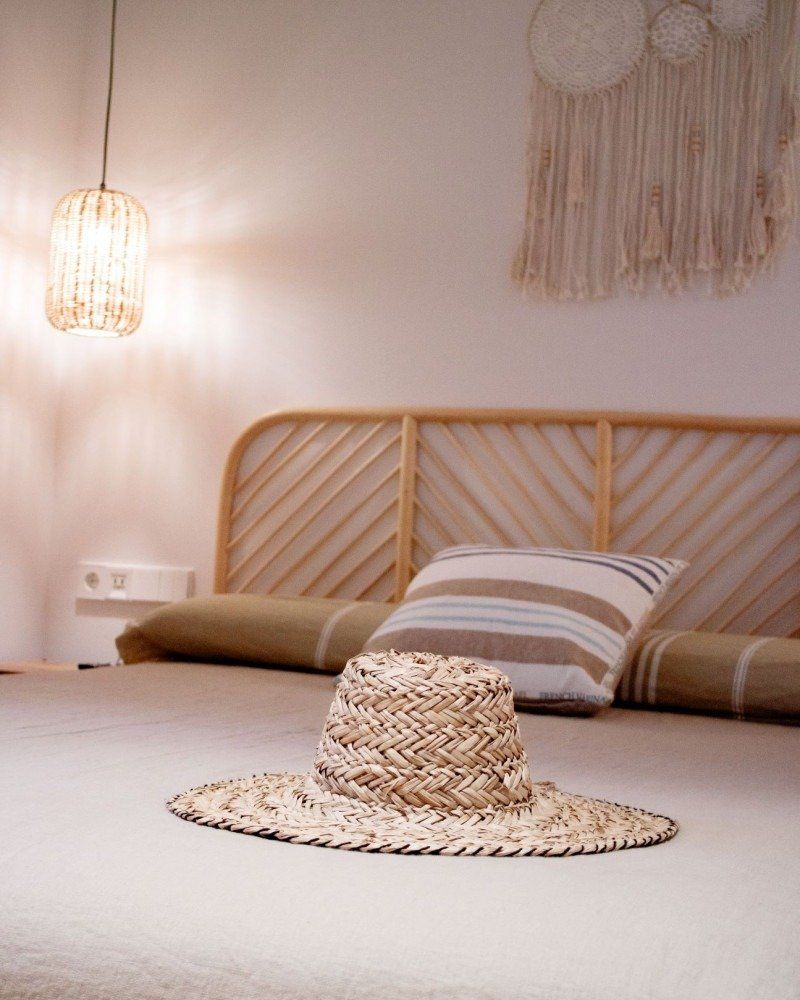 A straw hat is sitting on a bed in a bedroom