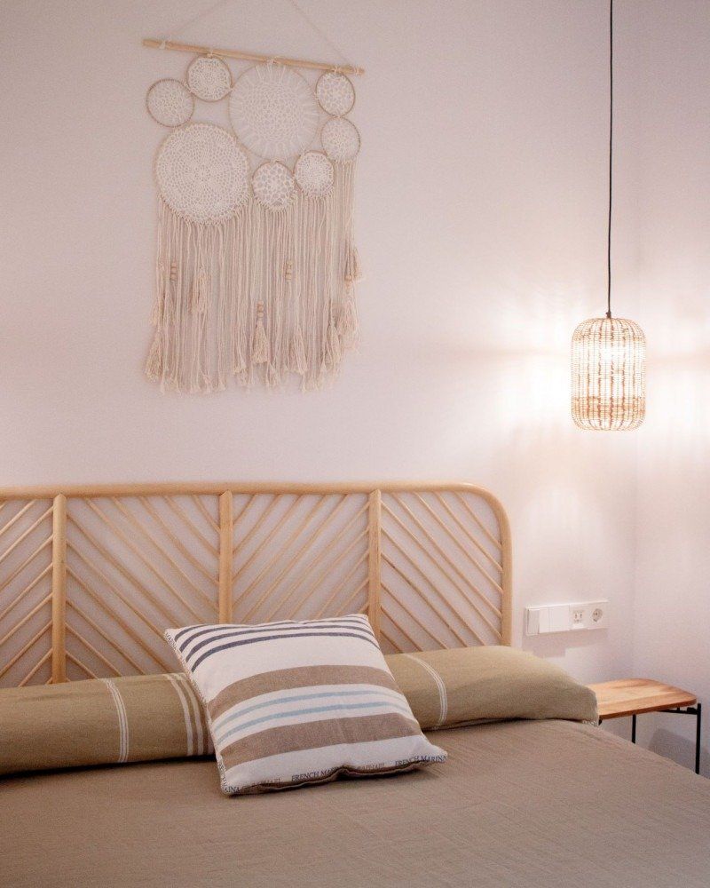 A bedroom with a wicker headboard and a striped pillow
