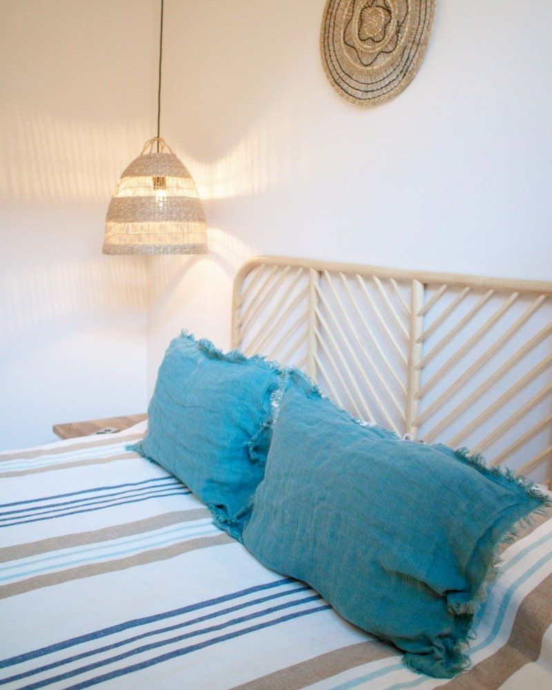 A bed with blue pillows and a lamp hanging from the ceiling