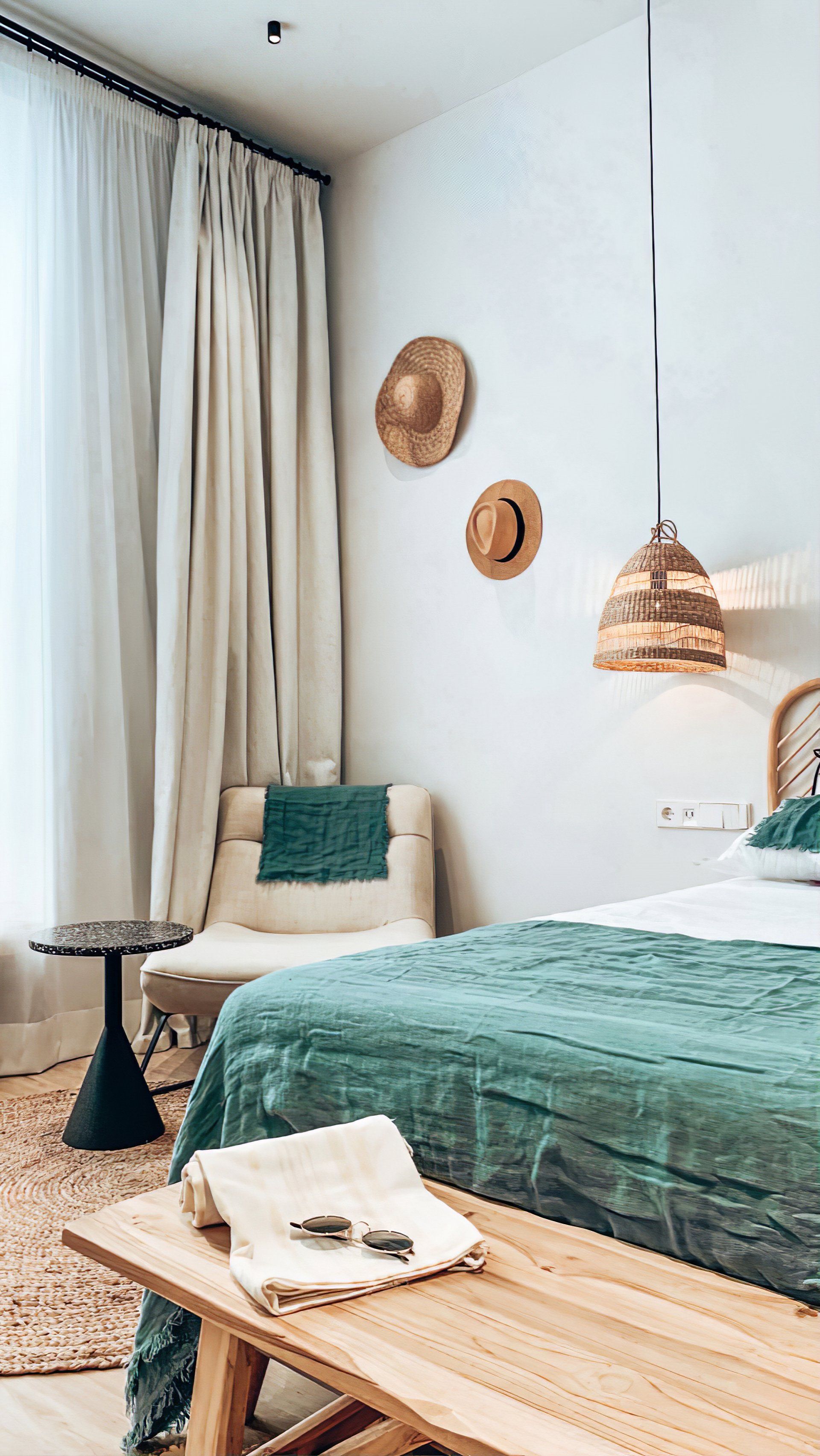 A bedroom with two beds , a chair , a table and a bench.