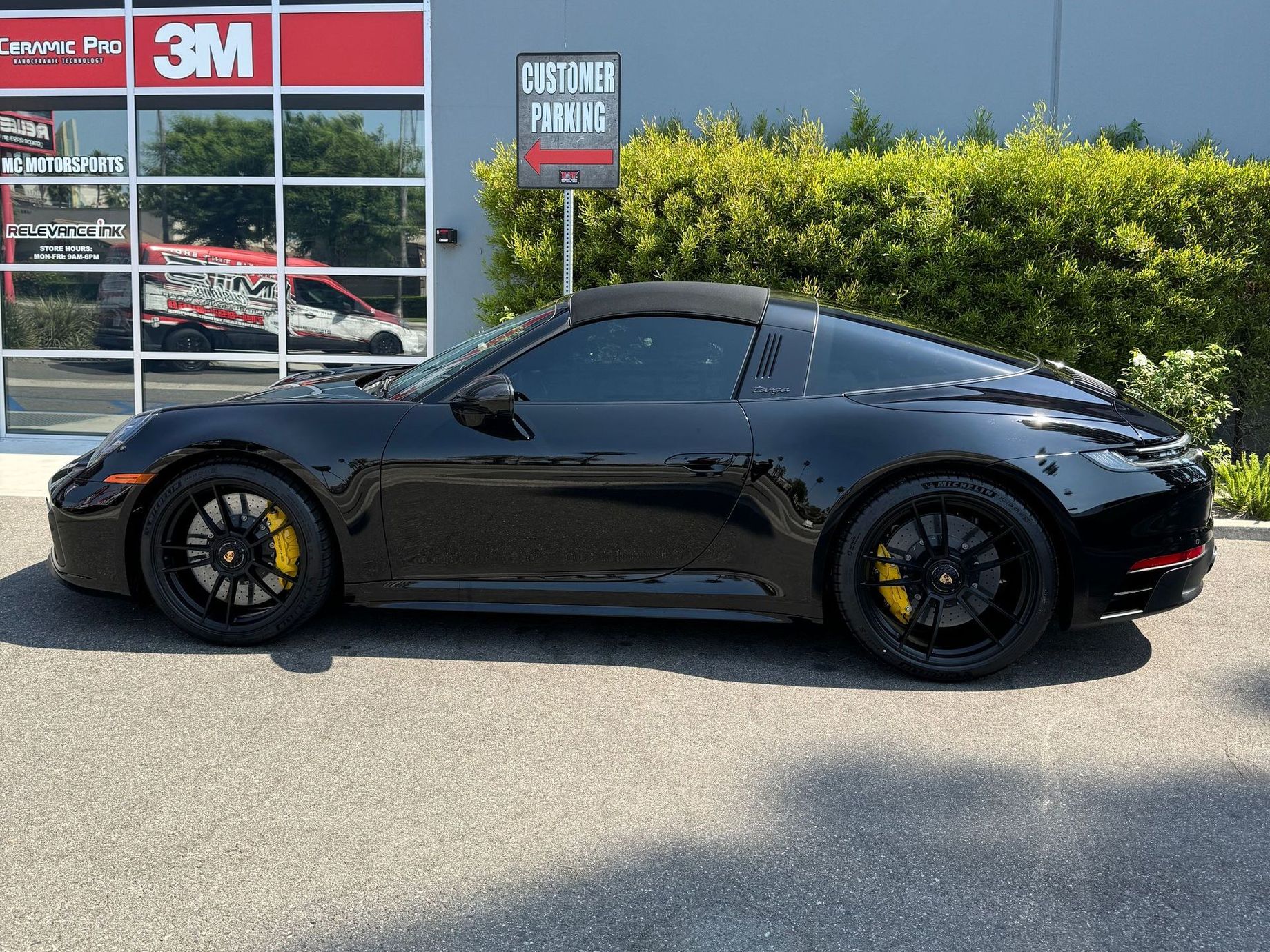 A black sports car is parked in front of a 3m store