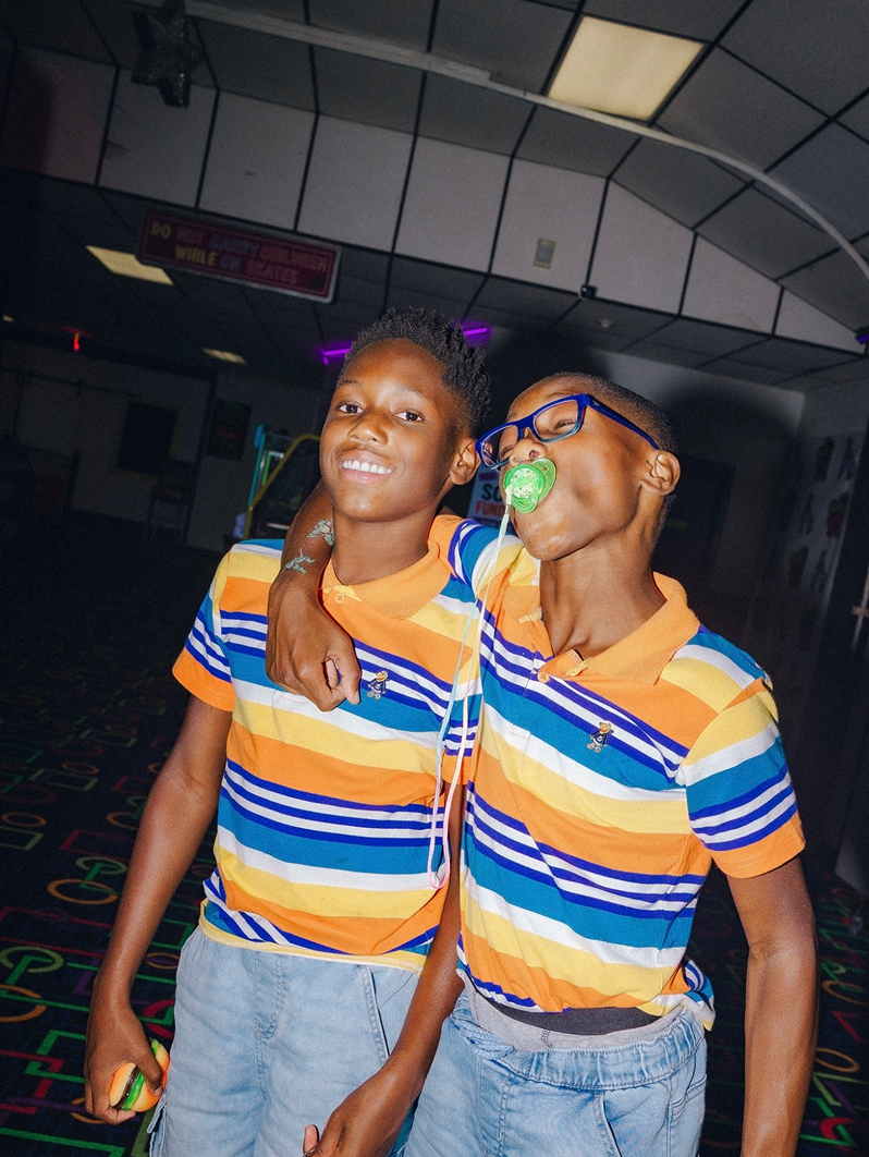 Two people in matching striped shirts pose together indoors, smiling with one arm around the other.