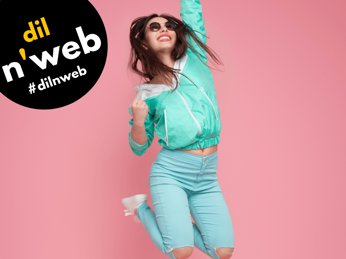 Woman in teal outfit jumps for joy against a pink background; 