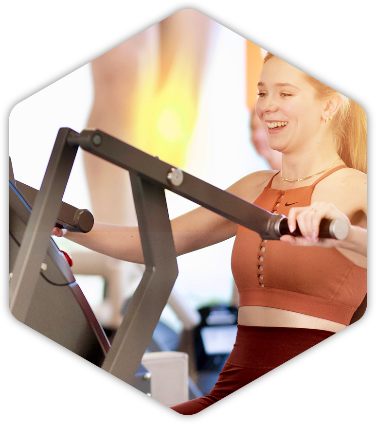 Eine Frau lächelt, während sie in einem Fitnessstudio ein Gerät benutzt