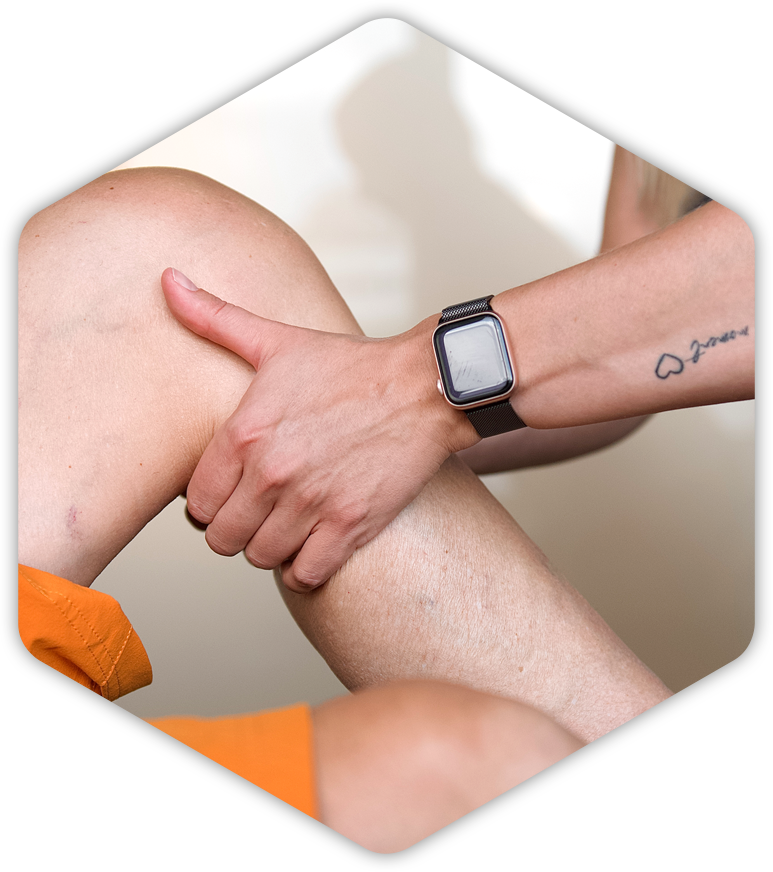Eine Person mit einer Uhr am Handgelenk hält das Bein einer anderen Person