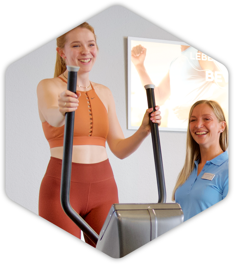 Eine Frau lächelt, während sie auf einem Crosstrainer trainiert
