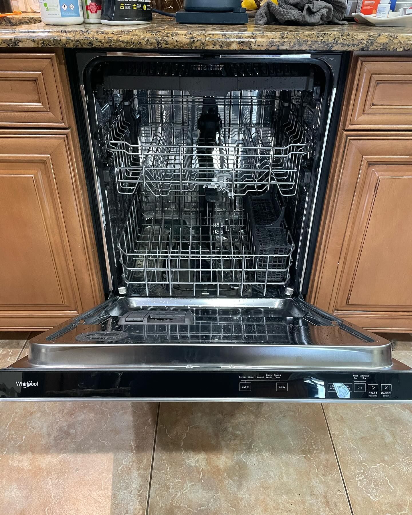 A dishwasher is open in a kitchen with the door open.