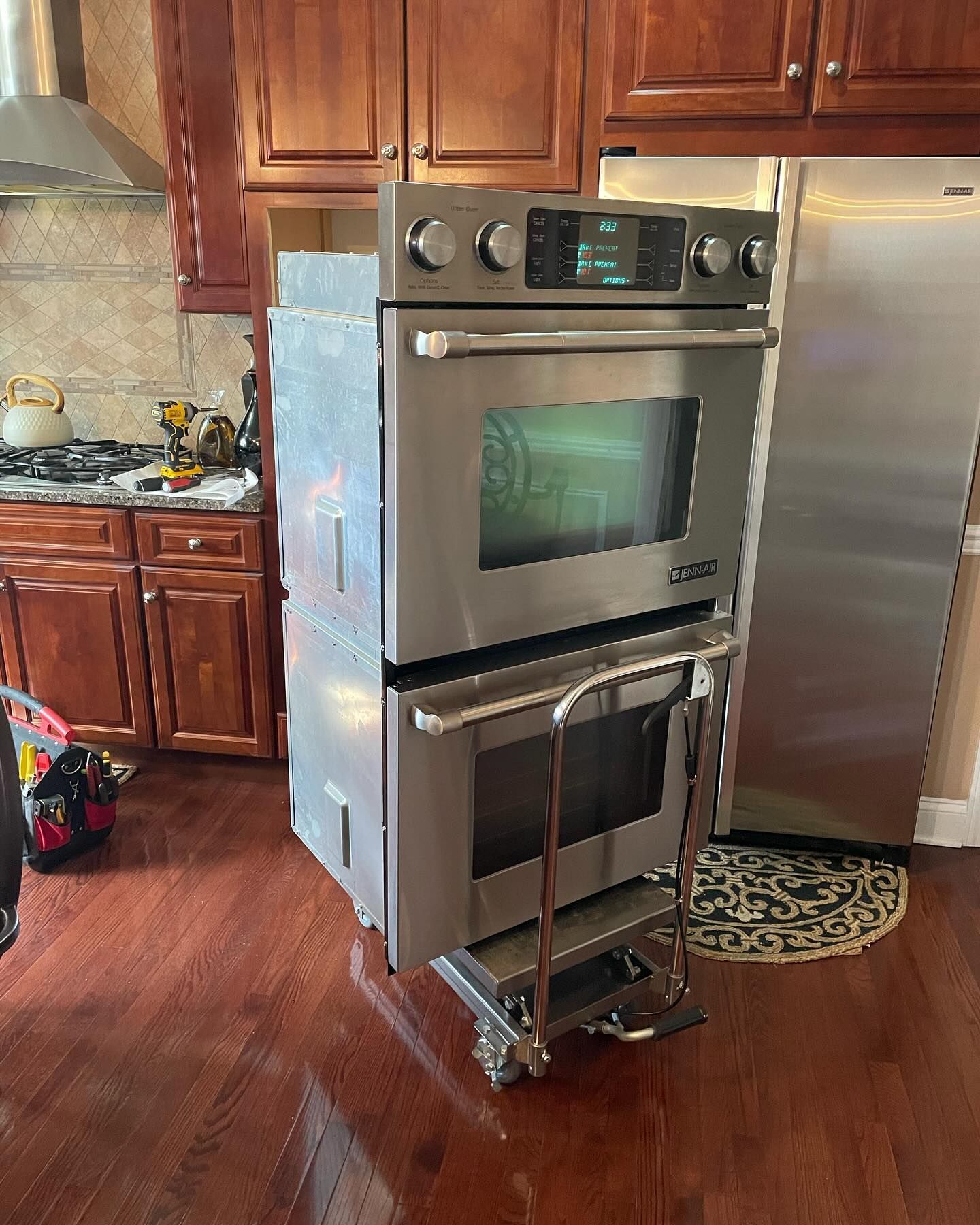 A stainless steel oven is sitting on a cart in a kitchen.