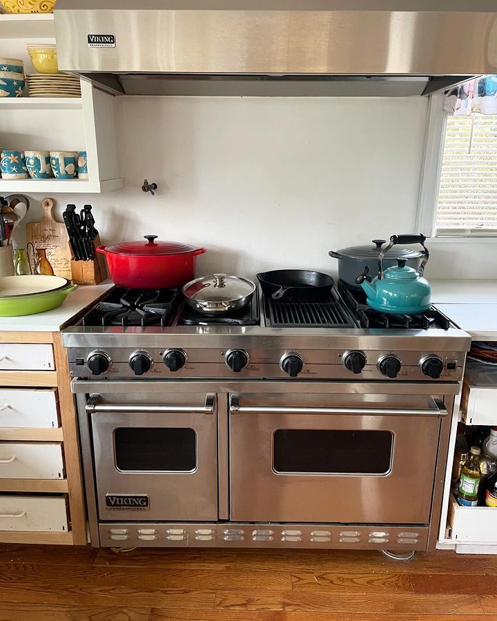 A kitchen with a stainless steel stove top oven and pots and pans on it.