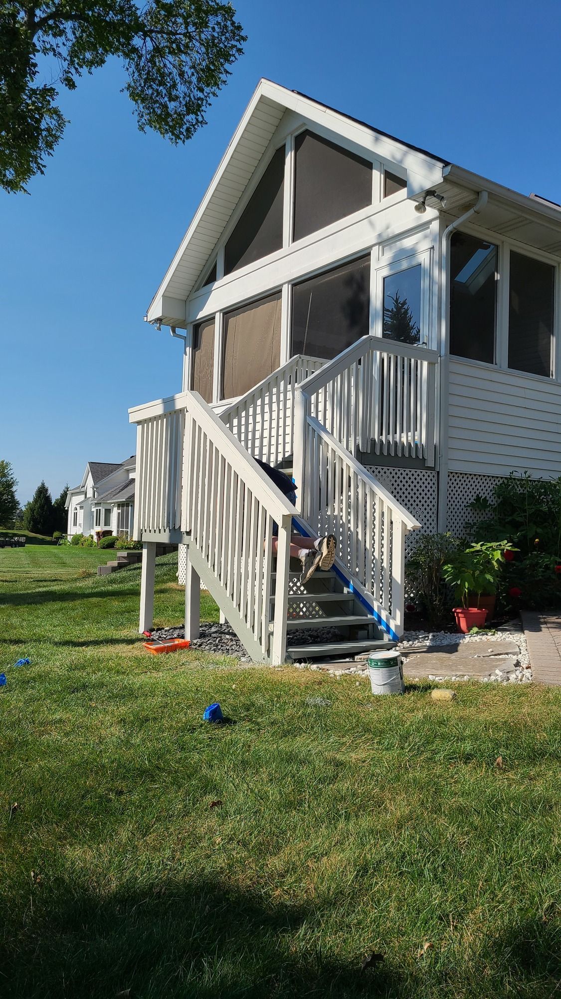 A white house with a screened in porch and stairs.