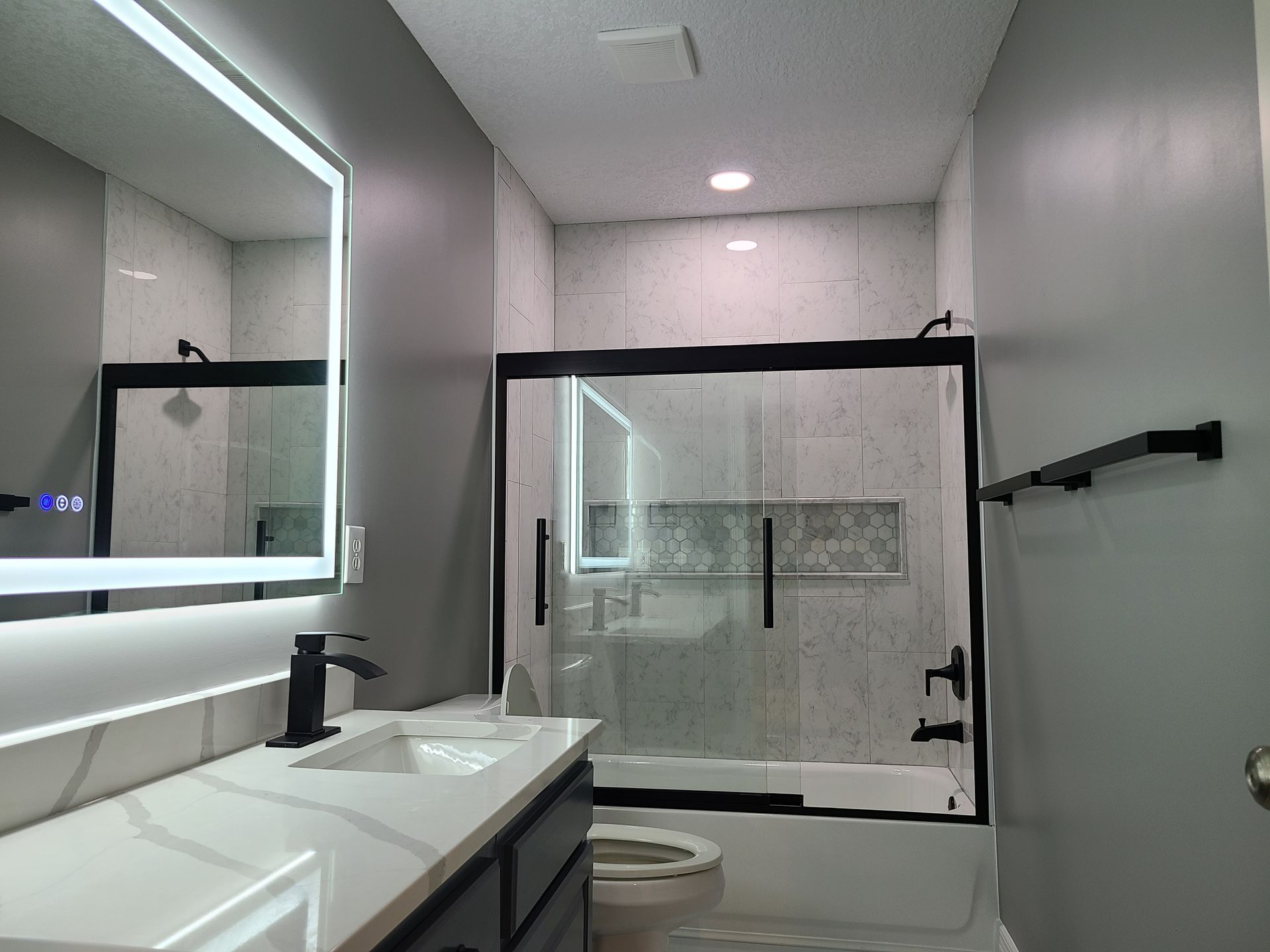 A bathroom with a sink , toilet , shower and mirror.