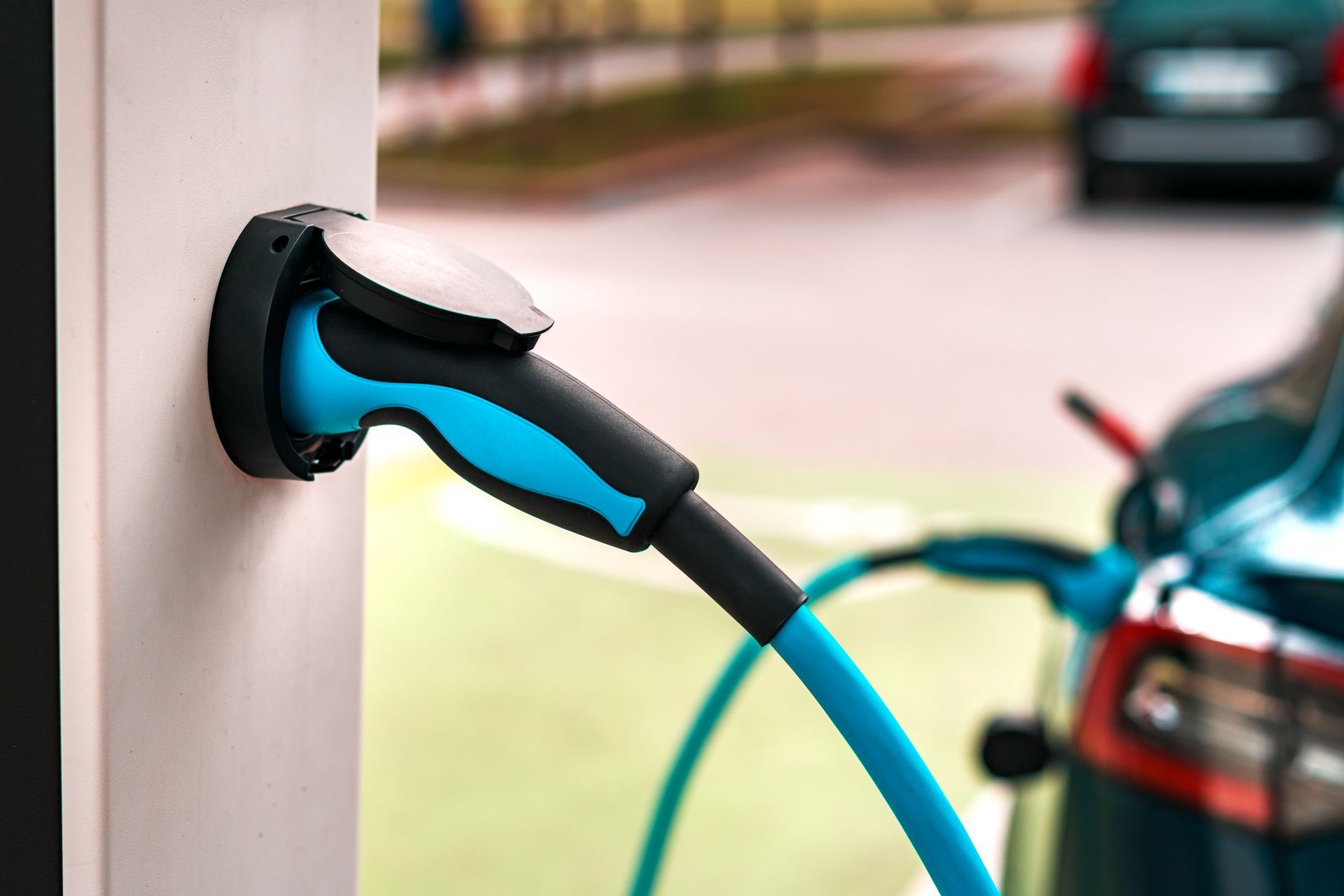 Blue electric car charging plug connected to a vehicle at a charging station