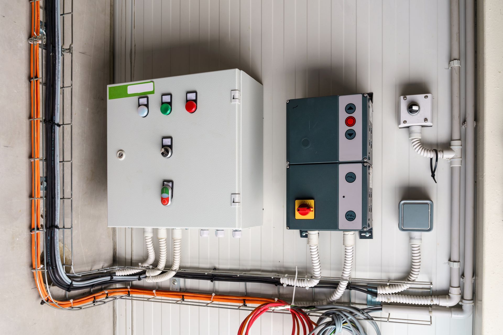Electrical control boxes and conduit mounted on a wall, with labeled switches and wiring.