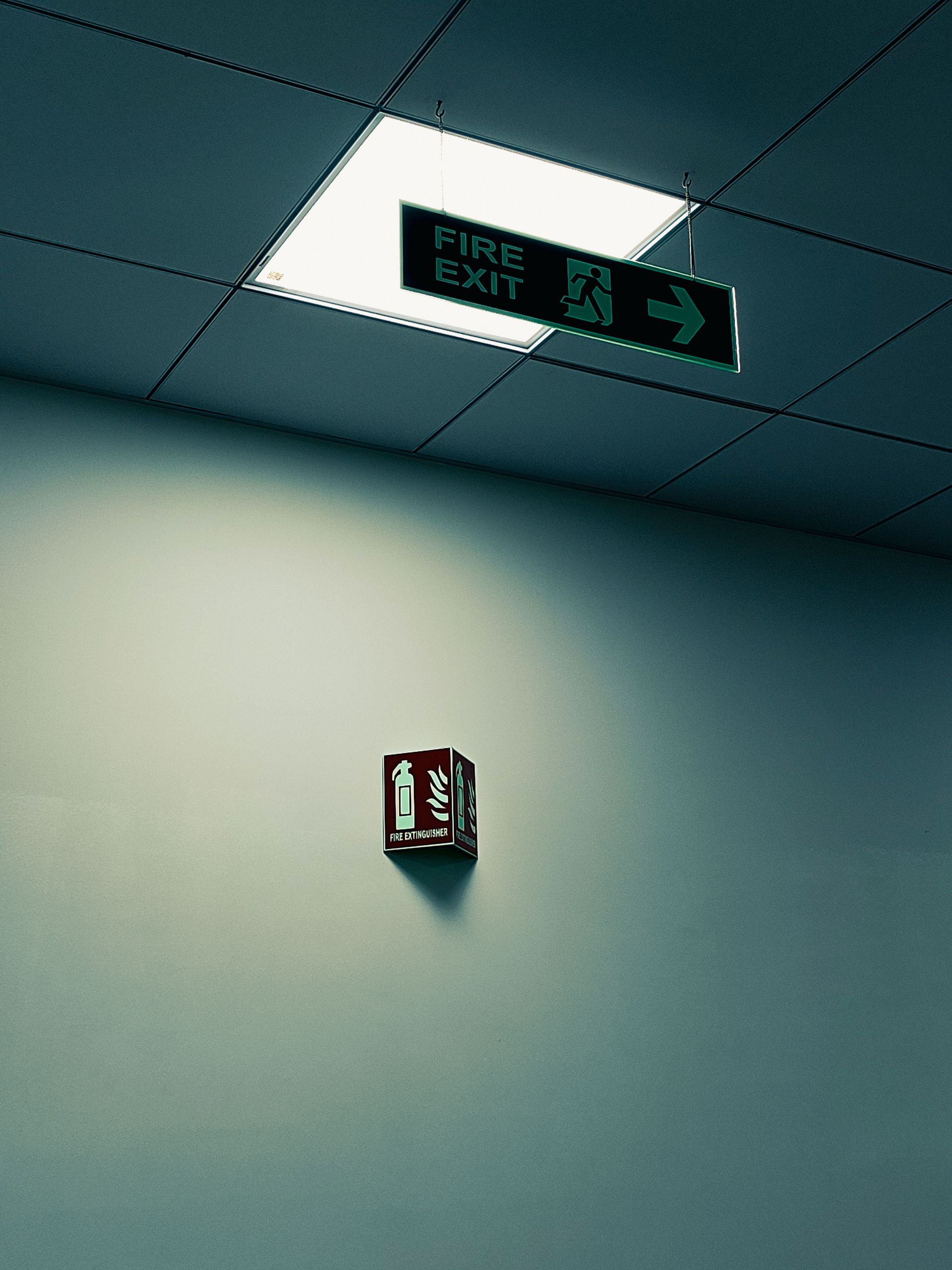 Illuminated emergency exit sign above a door in a South Florida commercial office corridor