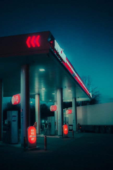 Neon-lit gas station at night with red signs and teal glow