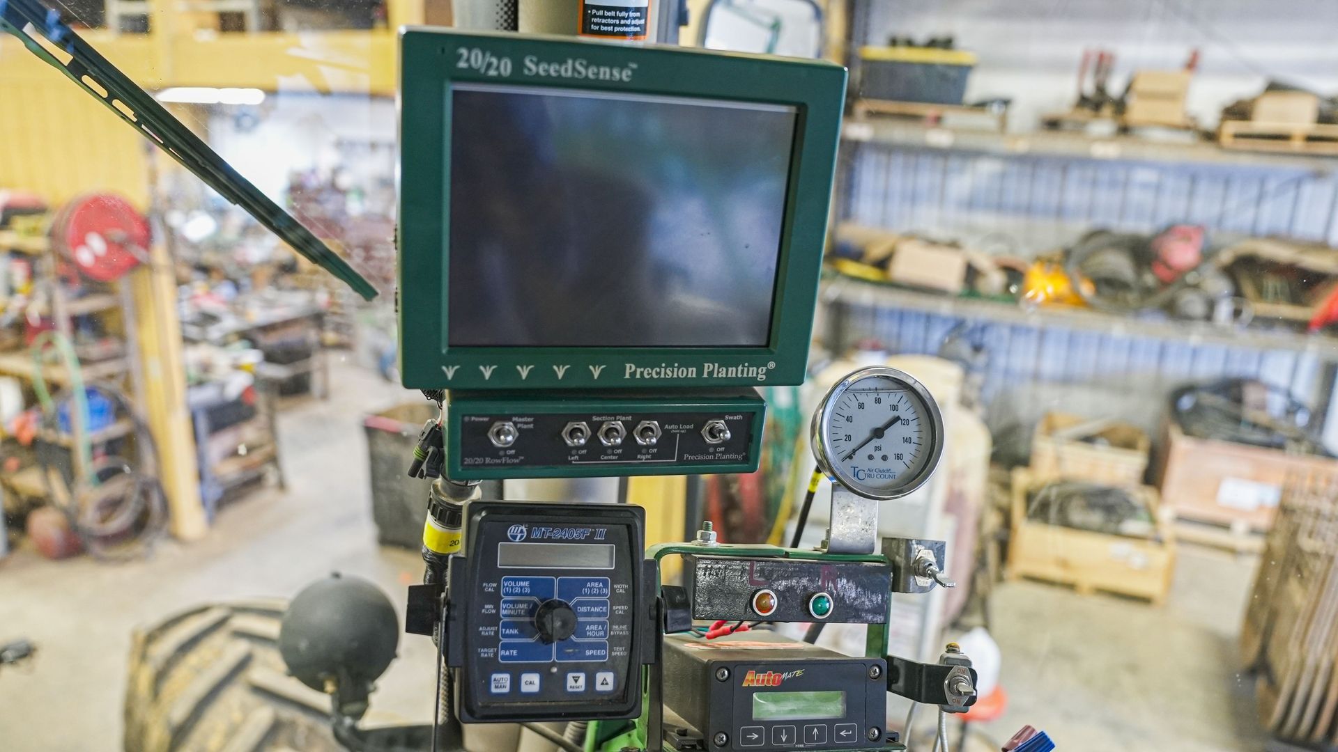 Workbench with a monitor, gauge, and electronics in a cluttered workshop, viewed in first-person setup