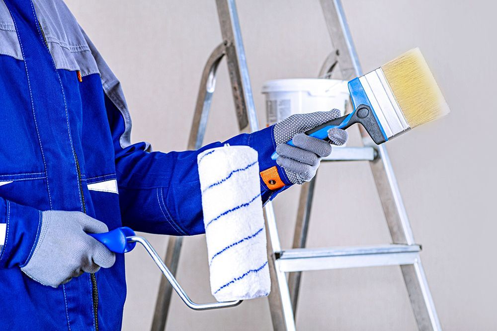 Worker Holding Paint Brush And Roller