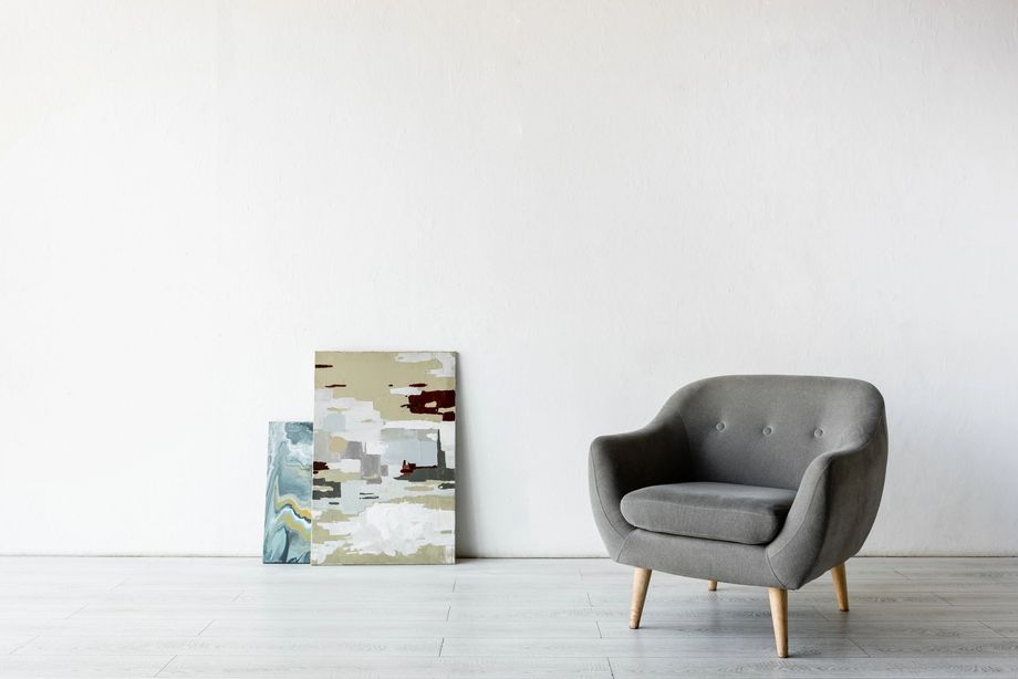 Poltrona grigia minimalista accanto a un quadro astratto in una stanza bianca e luminosa